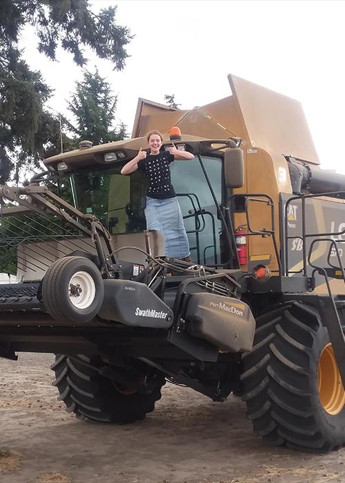 Girl giving the "thumbs up" on top of a big combine