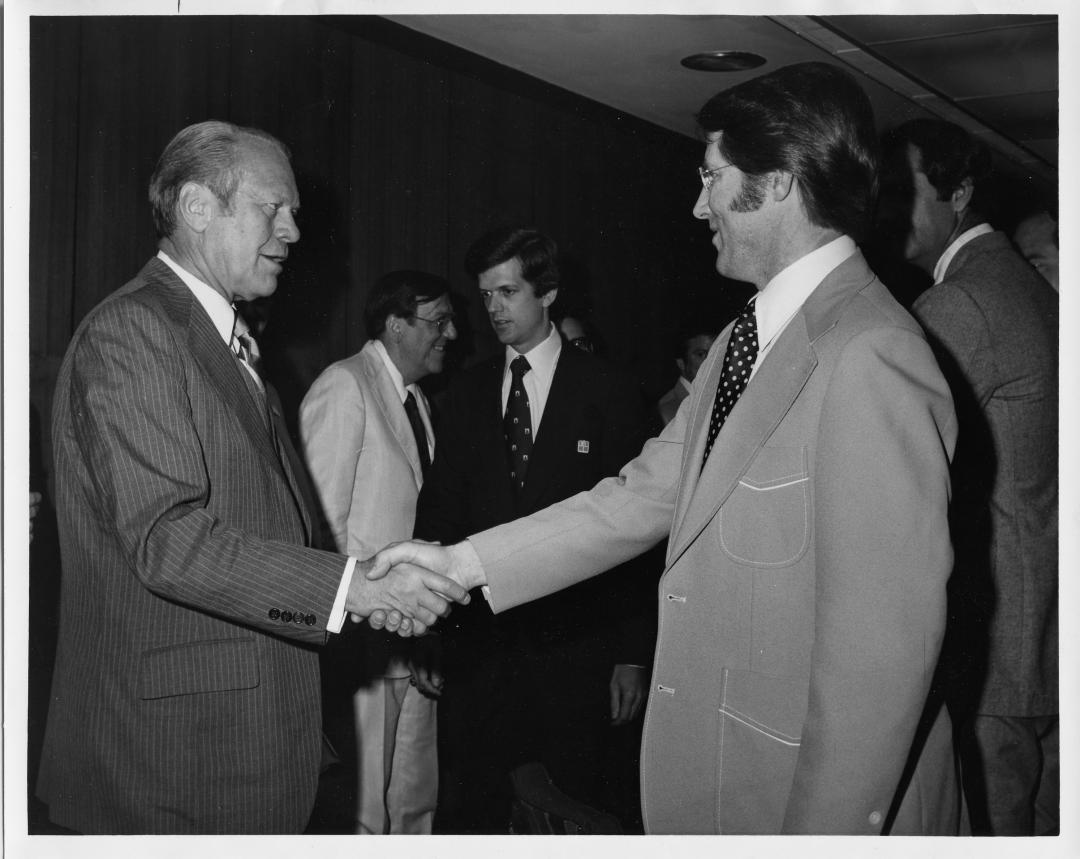 Two men shake hands.