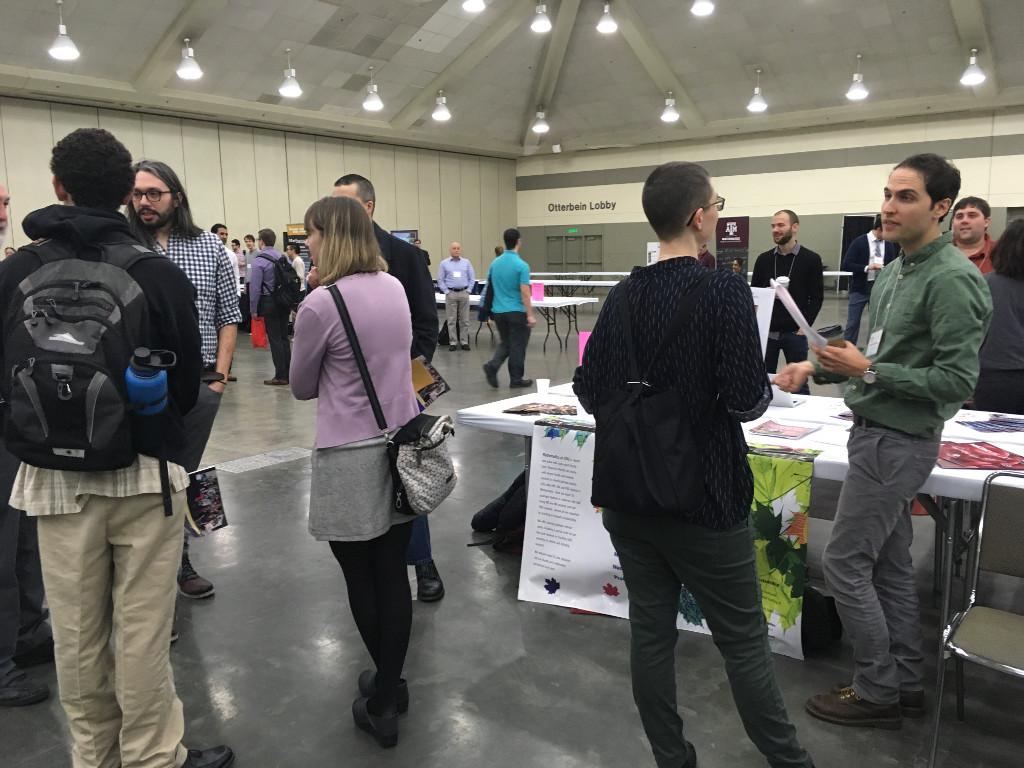 Students standing around a table during the JMM Fair 2019.