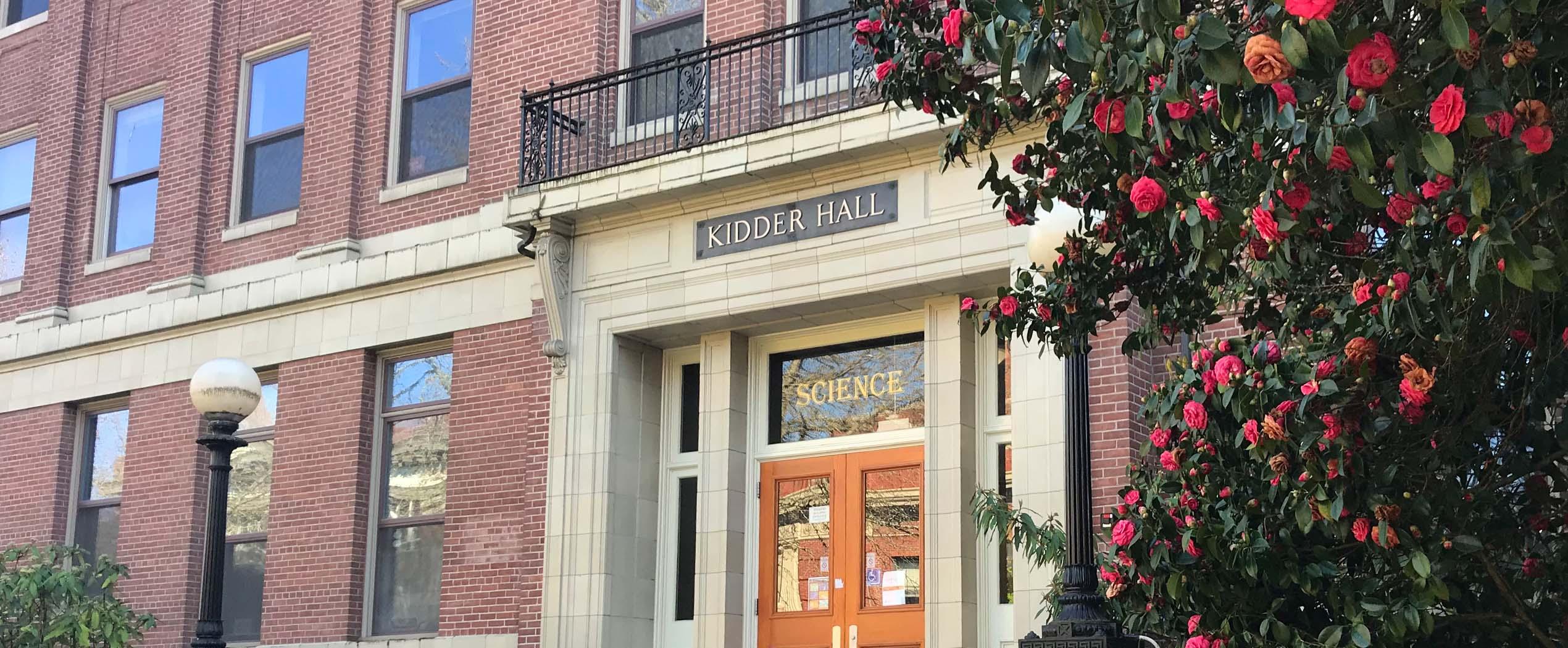 Front of Kidder hall with flowers in foreground.