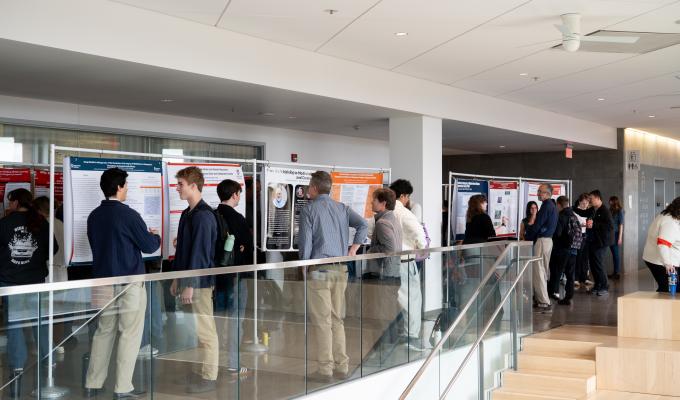 Students wander around looking at thesis posters.
