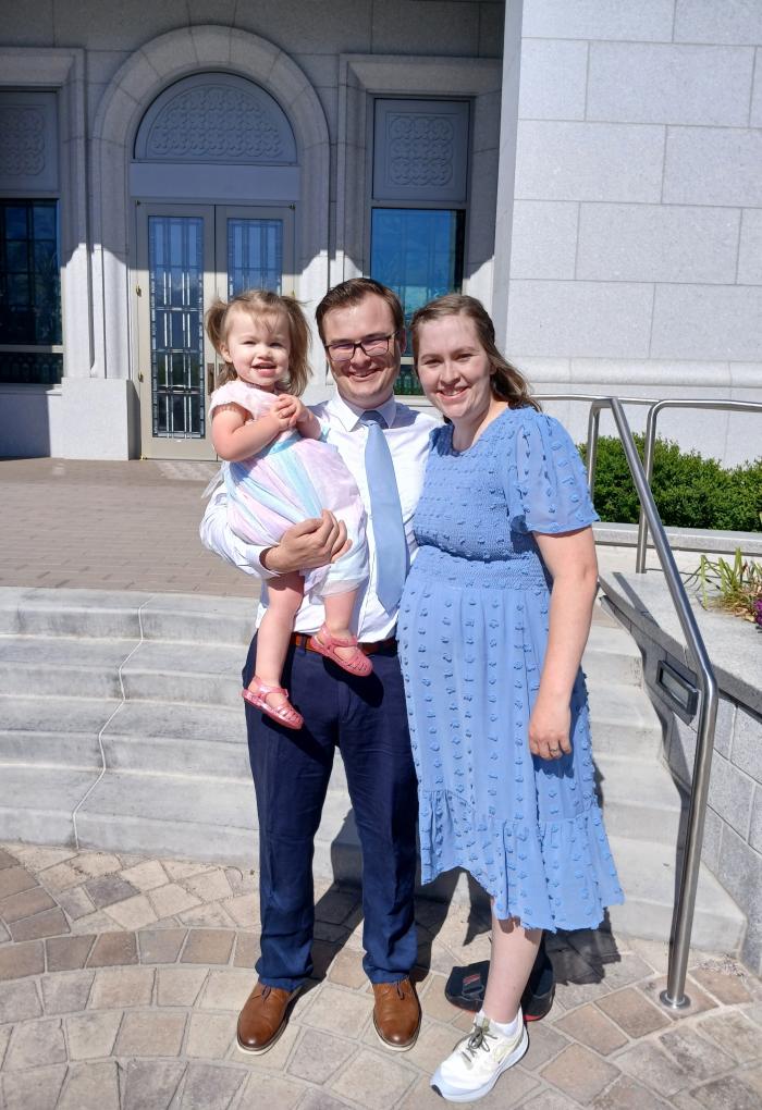 A man and woman pose for a photo with a young child.