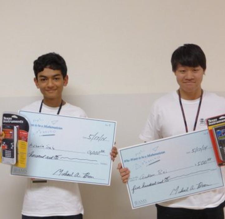 two male students holding awards in front of white backdrop
