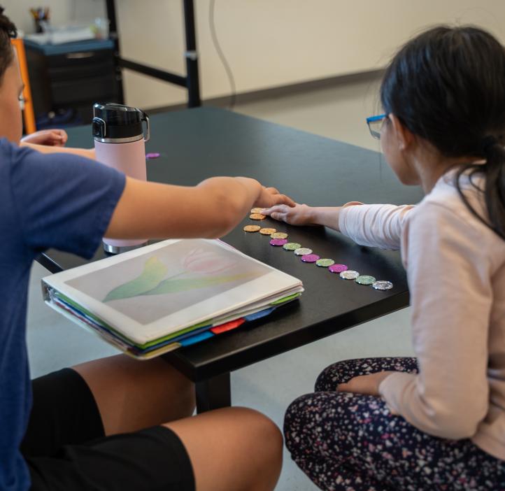 Two young kids work play with math tokens.